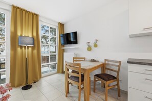 A modern room with a dining table, chairs, a TV mounted on the wall, a lamp, and a window with curtains.