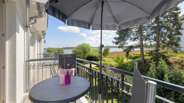 Ein Balkon mit einem Tisch, einer violetten Vase und einem rosa Kerzenleuchter.