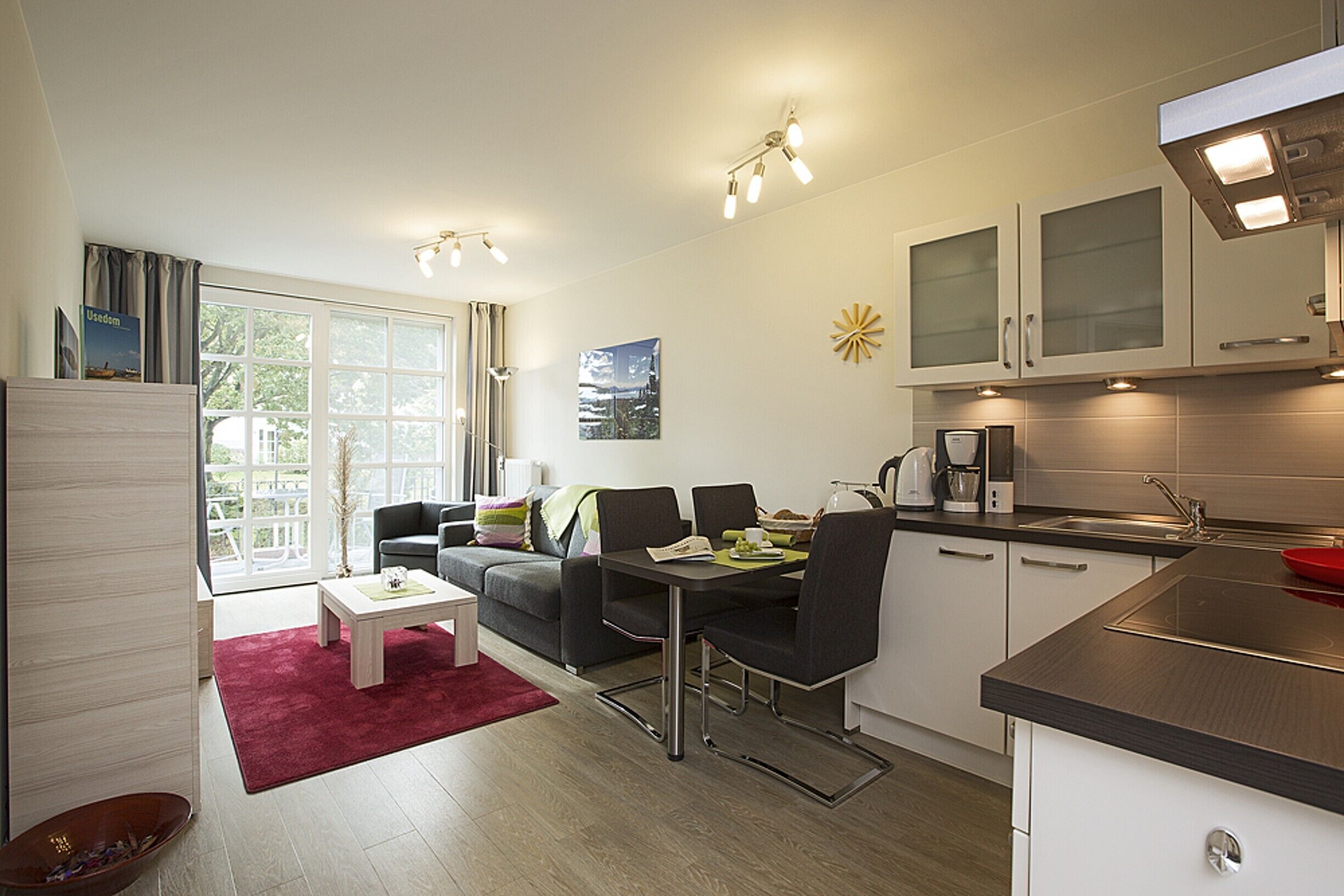 A modern kitchen with a dining area, a coffee machine, and a view of the outdoors.