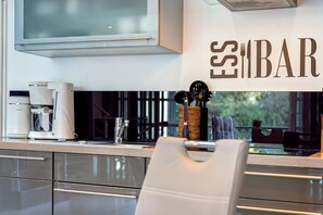 A modern kitchen with a coffee maker, utensils, and a sign that reads 'ESS BAR'. - Balmer See Residence, Apartment 70 with sauna, Wi-Fi, and 1 bedroom for 2 people (Balm)
