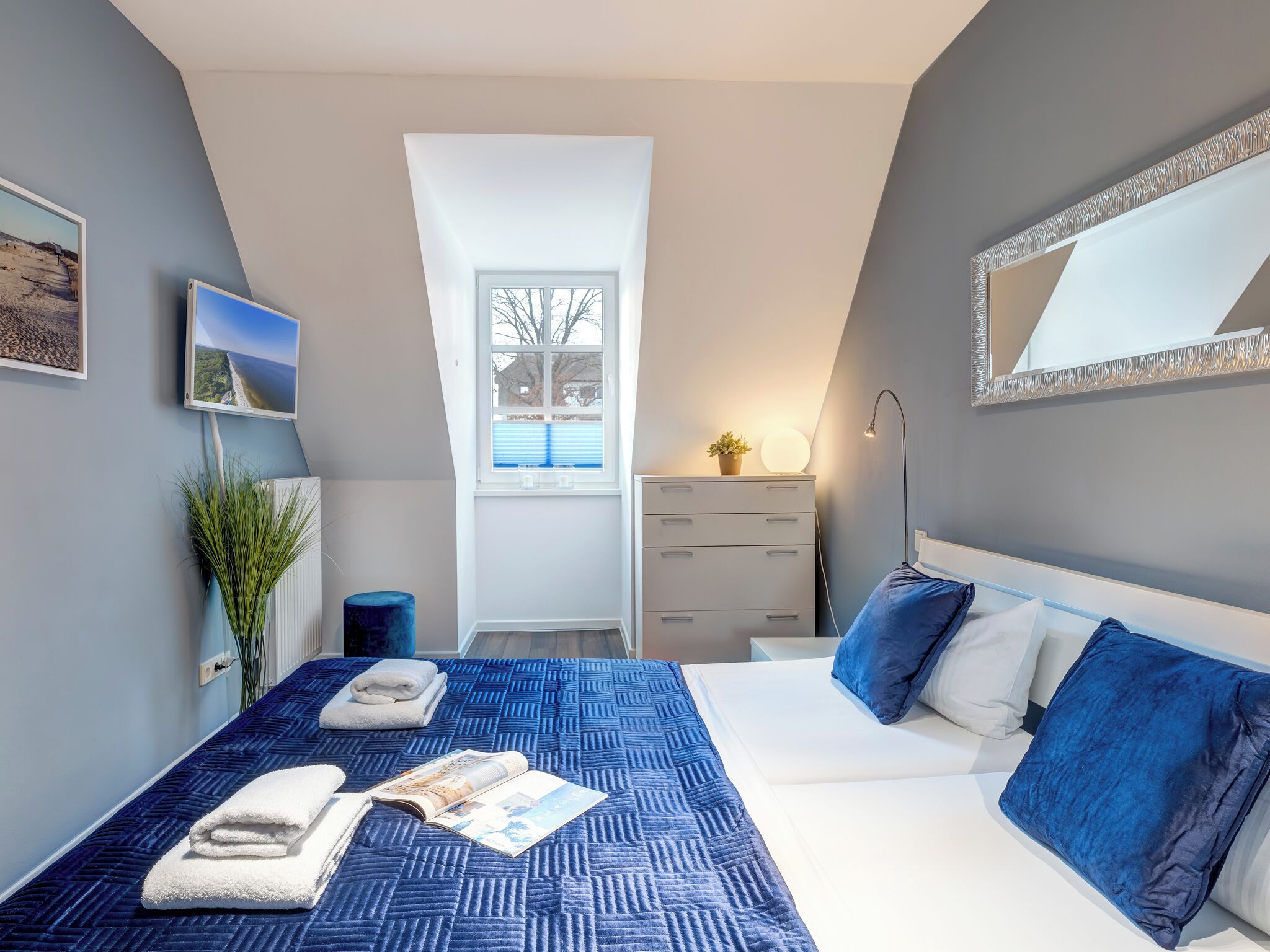 A bedroom with a large bed, a dresser, a mirror, and a window.