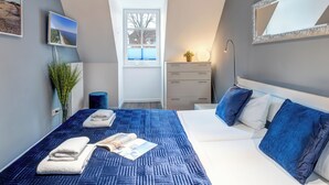 Quarto com cama grande, penteadeira, espelho e janela.