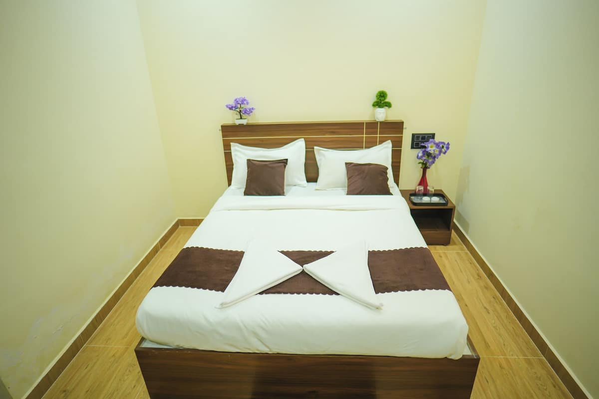 A neatly made bed with a wooden headboard, a nightstand with a vase of flowers, and a small potted plant on the wall.