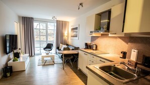 A modern kitchen with a sink, countertop, and a dining area with a table and chairs. - Residenz am Balmer See, apartment 21 with sauna, WLAN and 50 m to the lake (Balm)