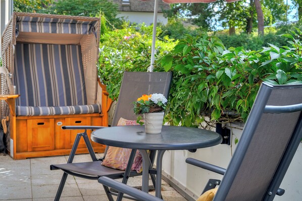 A patio area with a round table, two chairs, a cushioned bench, and a potted plant. - Residenz am Balmer See, Whg. 07 in Balm - peace, nature & wellness (Balm)