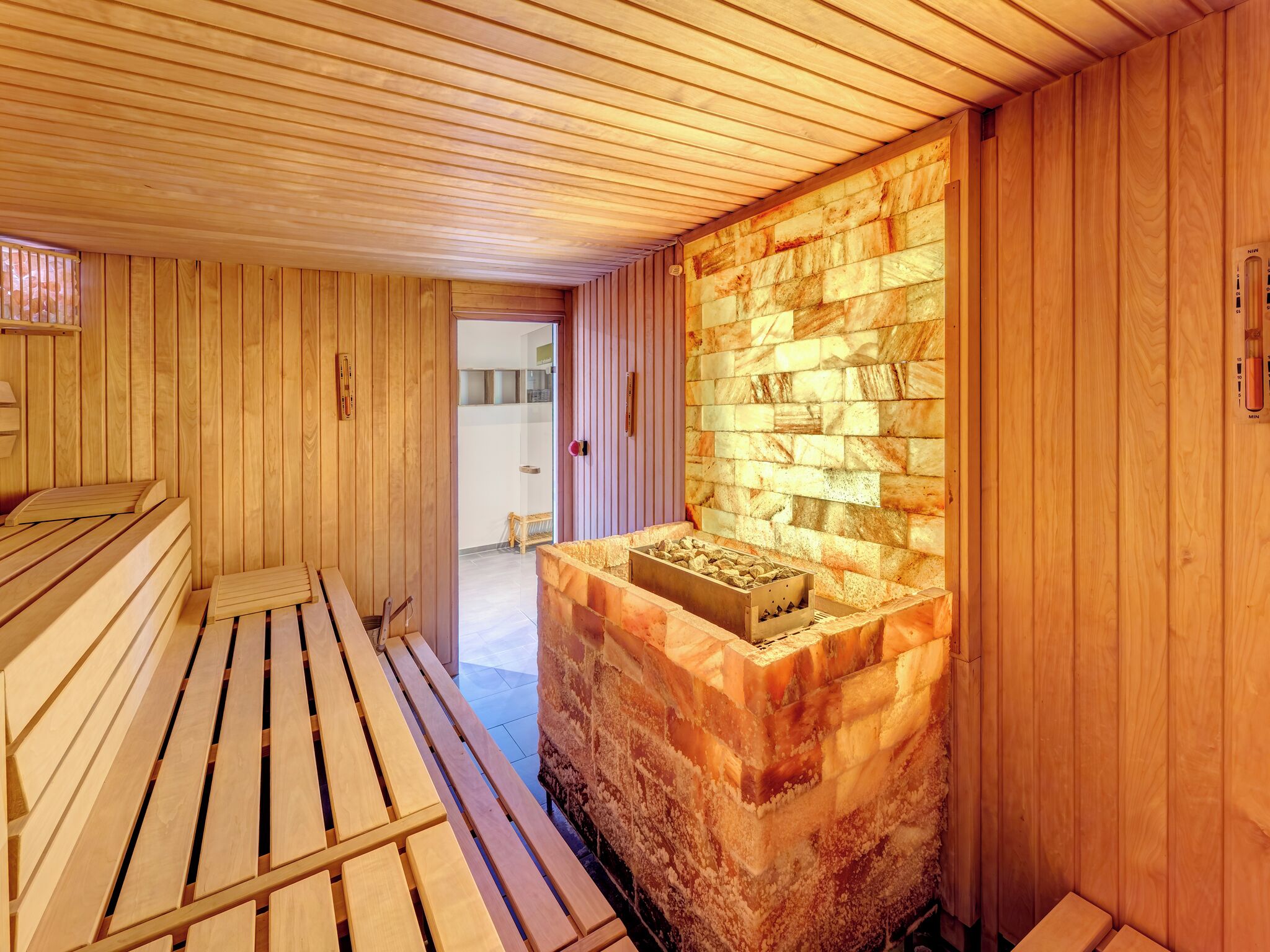 A sauna room with wooden benches and a stone wall.