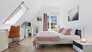 Une chambre à coucher avec un lit, un bureau, une chaise, une télévision et une fenêtre avec des rideaux.