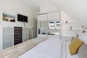 Quarto com cama, televisão, guarda-roupa e espelho.