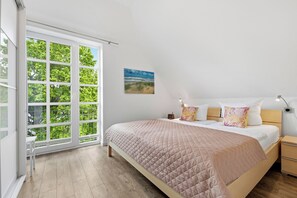 A bedroom with a large window, a bed with a quilted bedspread, a bedside table, and a nightstand. - Residenz am Balmer See, apartment 32 - with sauna and lake view (Balm)