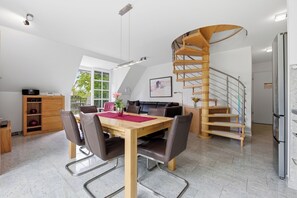 A modern kitchen with a wooden dining table, chairs, a spiral staircase, and a refrigerator. - Residenz am Balmer See, apartment 32 - with sauna and lake view (Balm)