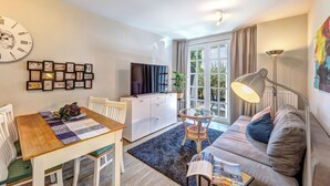 A modern living room with a dining table, sofa, TV, and artwork on the wall. - Residenz am Balmer See, apartment 35 with sauna and wellness by the lake (Balm)