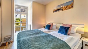 A bedroom with a large bed, a window, and a painting on the wall. - Residenz am Balmer See, apartment 35 with sauna and wellness by the lake (Balm)