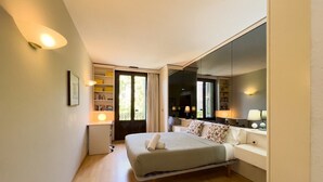 Un dormitorio moderno con cama, mesitas de noche, un espejo grande y una estantería.