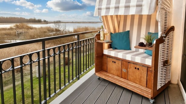 Una terraza de madera con un toldo a rayas y un área de estar acolchada con cojines.