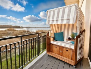 Una terraza de madera con un toldo a rayas y un área de estar acolchada con cojines.