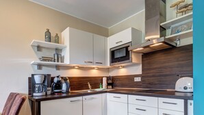 Una cocina moderna con armarios blancos, microondas integrado y cafetera.