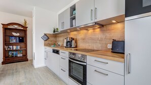 A modern kitchen with white cabinetry, a wooden countertop, and stainless steel appliances. - Bernsteinquartier, apartment 05.49 "Ferienglück" in Kölpinsee - close to the beach & stylish (Kölpinsee)
