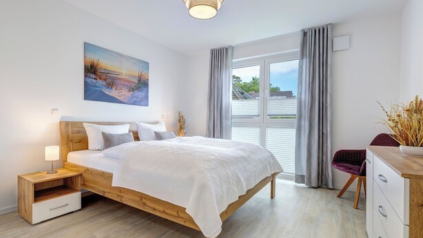 A modern bedroom with a wooden bed, bedside tables, a nightstand, a desk, and a chair. - Bernsteinquartier, apartment 05.49 "Ferienglück" in Kölpinsee - close to the beach & stylish (Kölpinsee)