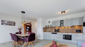 A modern kitchen with white cabinets, a wooden countertop, and a built-in oven. - Bernsteinquartier, apartment 05.49 "Ferienglück" in Kölpinsee - close to the beach & stylish (Kölpinsee)