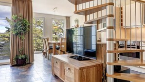 A modern living room with a large flat-screen TV, wooden furniture, and a staircase. - Ostseeresidenz Gorki Park, Whg. 18:20 m to the sandy beach, 5 star comfort (Heringsdorf)