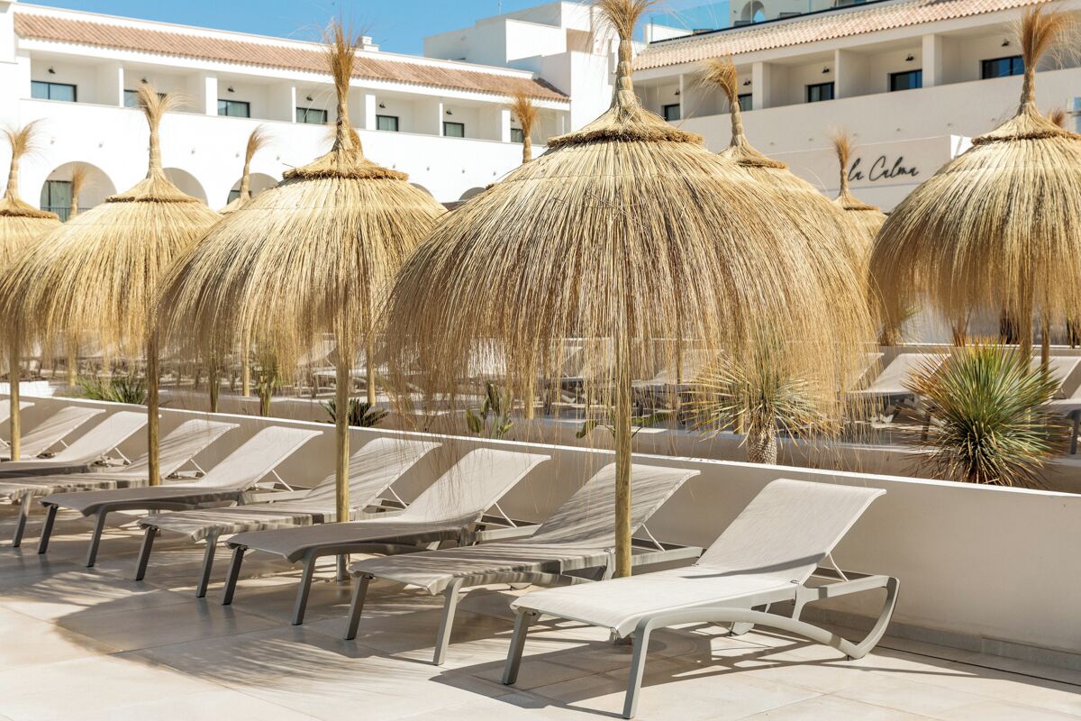 A poolside area with lounge chairs and thatched umbrellas.