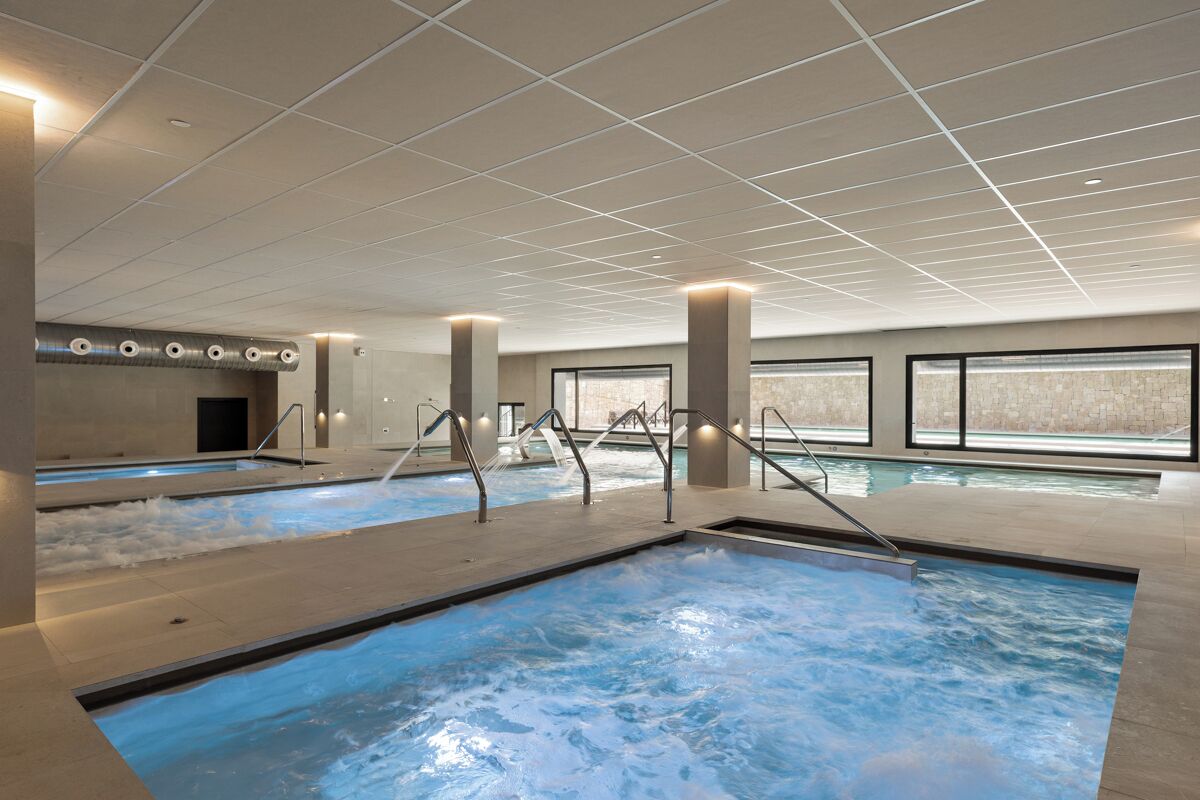 An indoor swimming pool with multiple lanes, clear water, and a modern ceiling design.