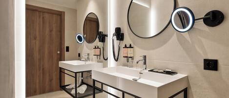 Un baño moderno con dos lavamanos, una puerta de madera y espejos montados en la pared.
