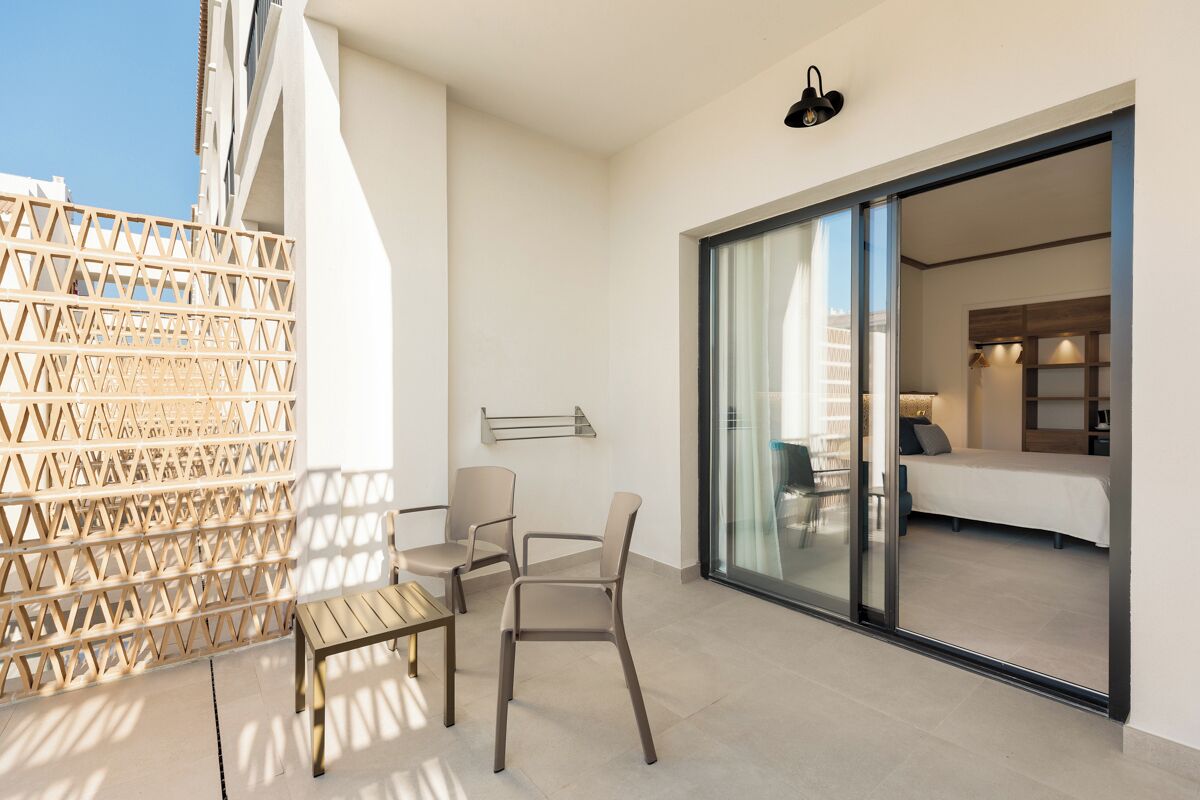 A balcony with a wooden lattice partition, a table, and two chairs.