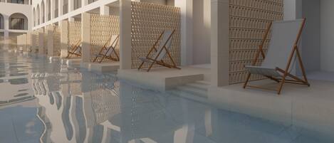 A spacious indoor pool area with clear reflections on the floor, surrounded by white walls and columns, and featuring wooden easels and chairs.