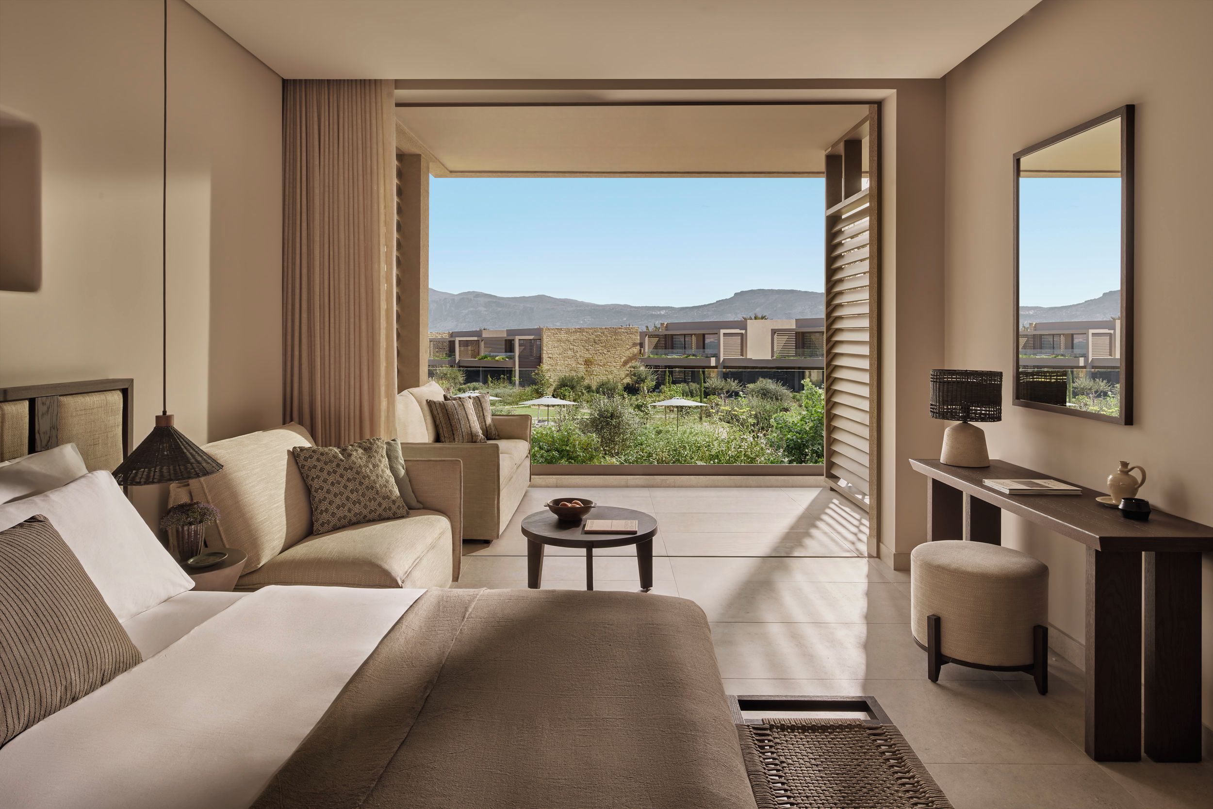 A hotel room with a bed, a desk, a chair, a small table, and a view of the outdoors.