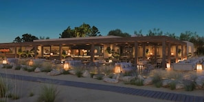 A modern outdoor dining area with multiple tables and chairs, surrounded by rocks and plants. - Ikos Kissamos - All Inclusive (Kissamos)