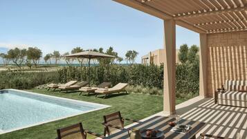 A poolside area with lounge chairs, a table with a pitcher and snacks, and a pergola with an umbrella.