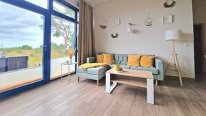 A modern living room with a large window, a sofa with yellow cushions, a coffee table, and a floor lamp.