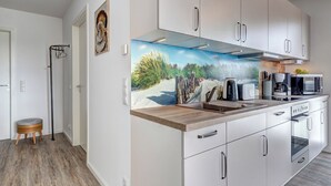 Una cocina moderna con armarios blancos, encimera de madera y un mural con motivos marinos.