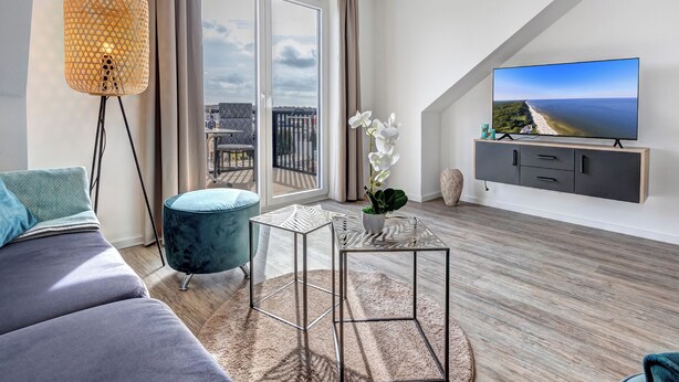 Una sala de estar moderna con un televisor grande, un sofá, una mesita y una lámpara de pie.