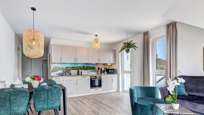 Una sala moderna con comedor, cocina y un ventanal grande.