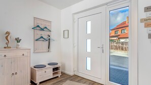 A modern interior with a wooden cabinet, a shoe rack, and a door leading outside. - Bernsteinquartier, vacation home 06b "Lachmöwe" in Kölpinsee - Baltic Sea vacation deluxe (Kölpinsee)