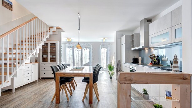 A modern kitchen with a central island, white cabinetry, and a wooden staircase. - Bernsteinquartier, vacation home 06b "Lachmöwe" in Kölpinsee - Baltic Sea vacation deluxe (Kölpinsee)