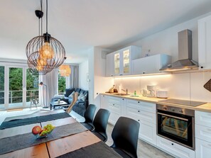A modern kitchen with white cabinets, a built-in oven, and a dining area with a table set for two.