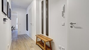A hallway with a wooden bench, white walls, and a door with a modern handle.