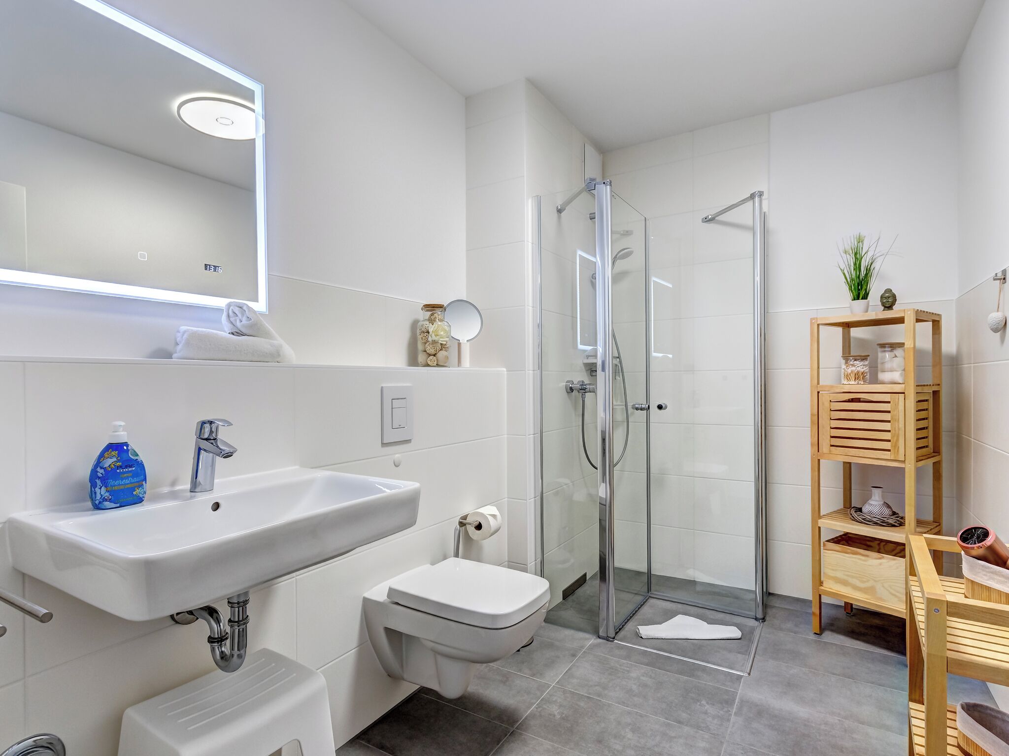 A modern bathroom with a white sink, toilet, and glass shower enclosure.