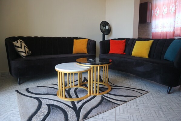 Relax in this stylish living room with a black sectional sofa, glass-top coffee table, and patterned rug.