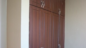 Een grote houten garderobe met meerdere deuren en handgrepen.