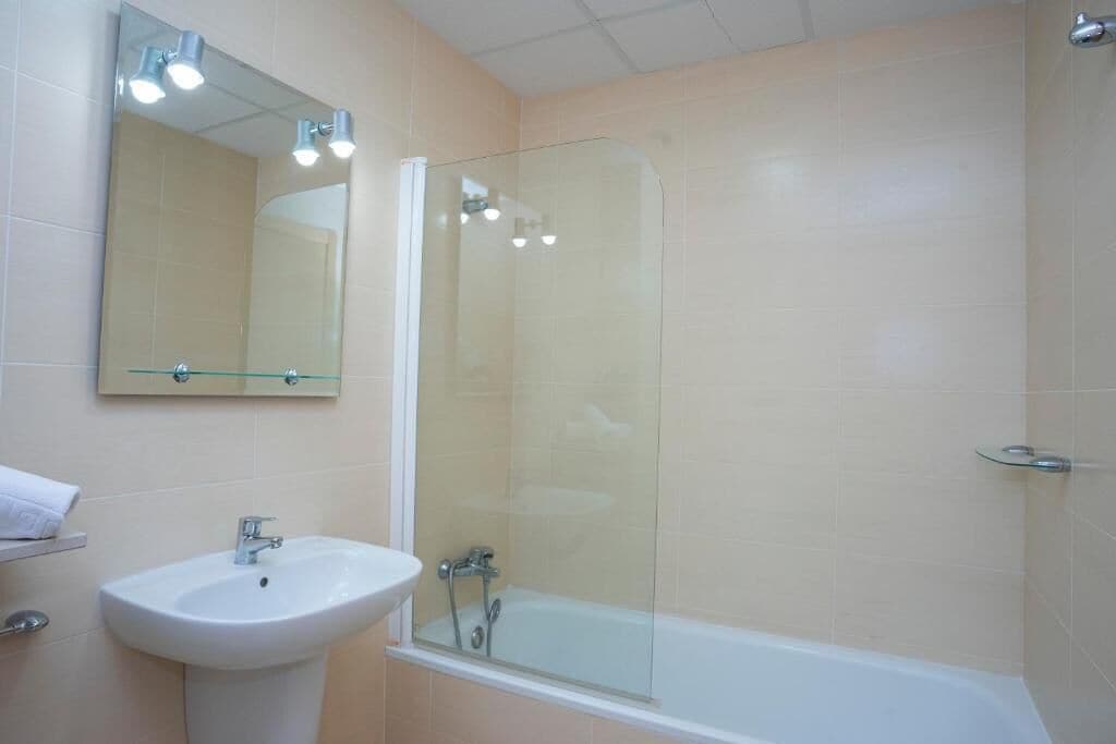 A bathroom with a glass-enclosed shower, a sink, and a mirror.