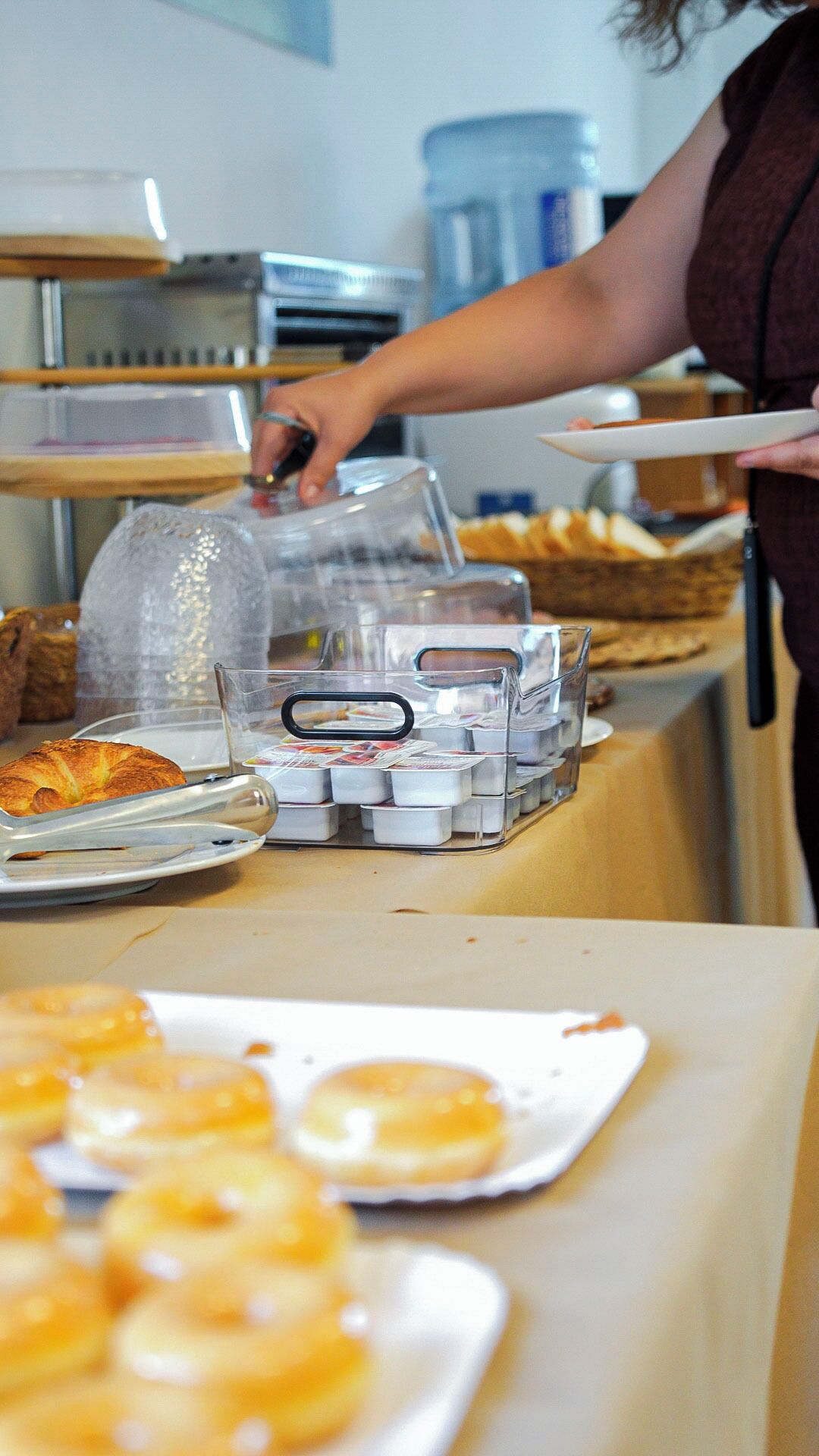 A buffet setup with various food items and a person serving.