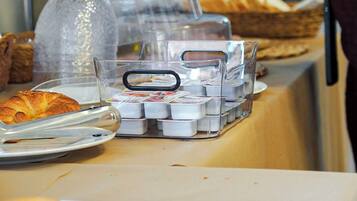 A buffet setup with various food items and a person serving.