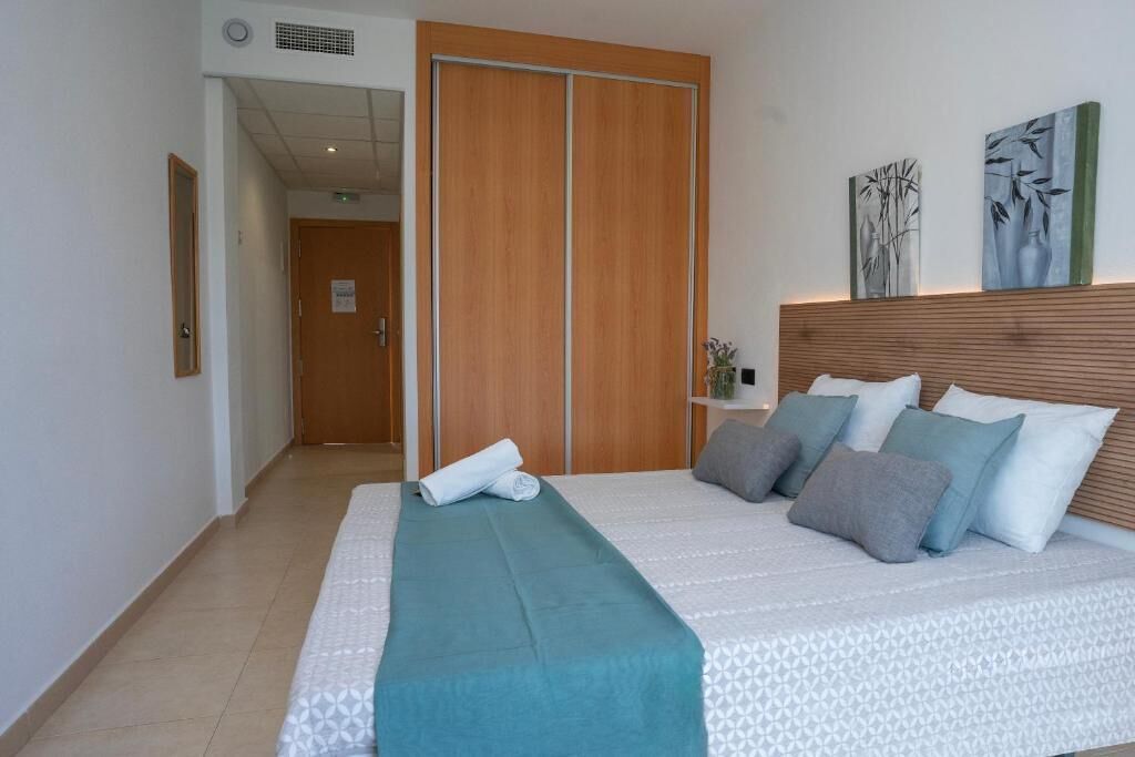 Una camera d'albergo con un letto, un armadio in legno e due opere d'arte appese al muro.