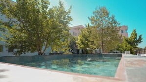 Une piscine extérieure entourée d’arbres et d’immeubles.