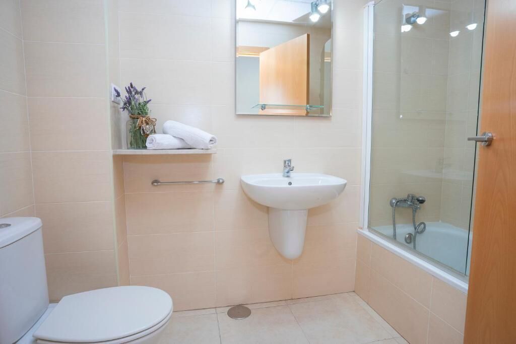 Un baño con inodoro, lavabo y cabina de ducha de vidrio.