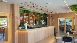 Un espace bar moderne avec un lambris en bois, un comptoir où sont exposées des bouteilles et un mur végétal.
